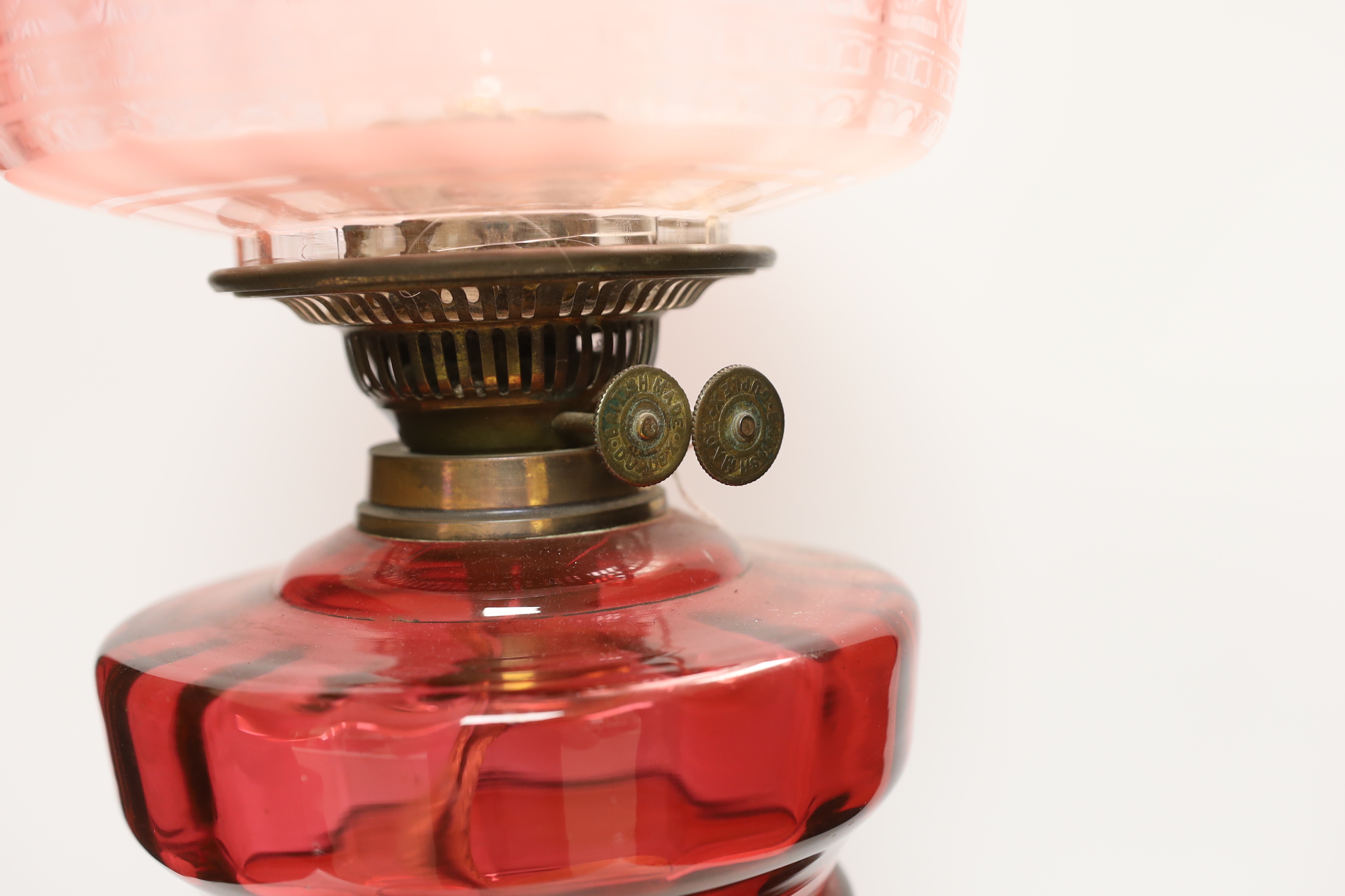 19th century brass oil lamp with cranberry glass reservoir, etched shade and Ruskin type cabochon panels to the base, 68cm high overall